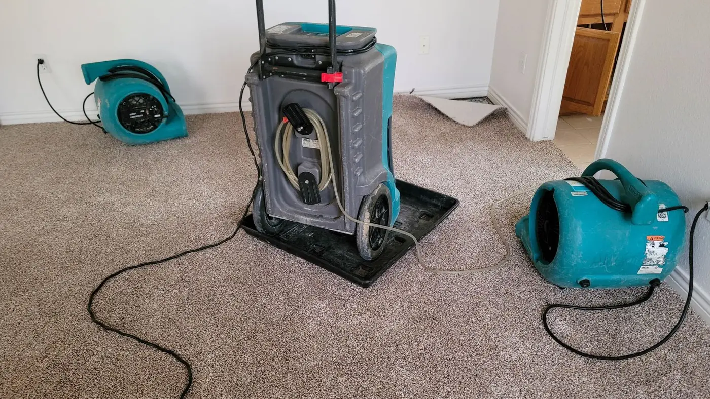 Dehumidifier and two air movers drying a carpeted room